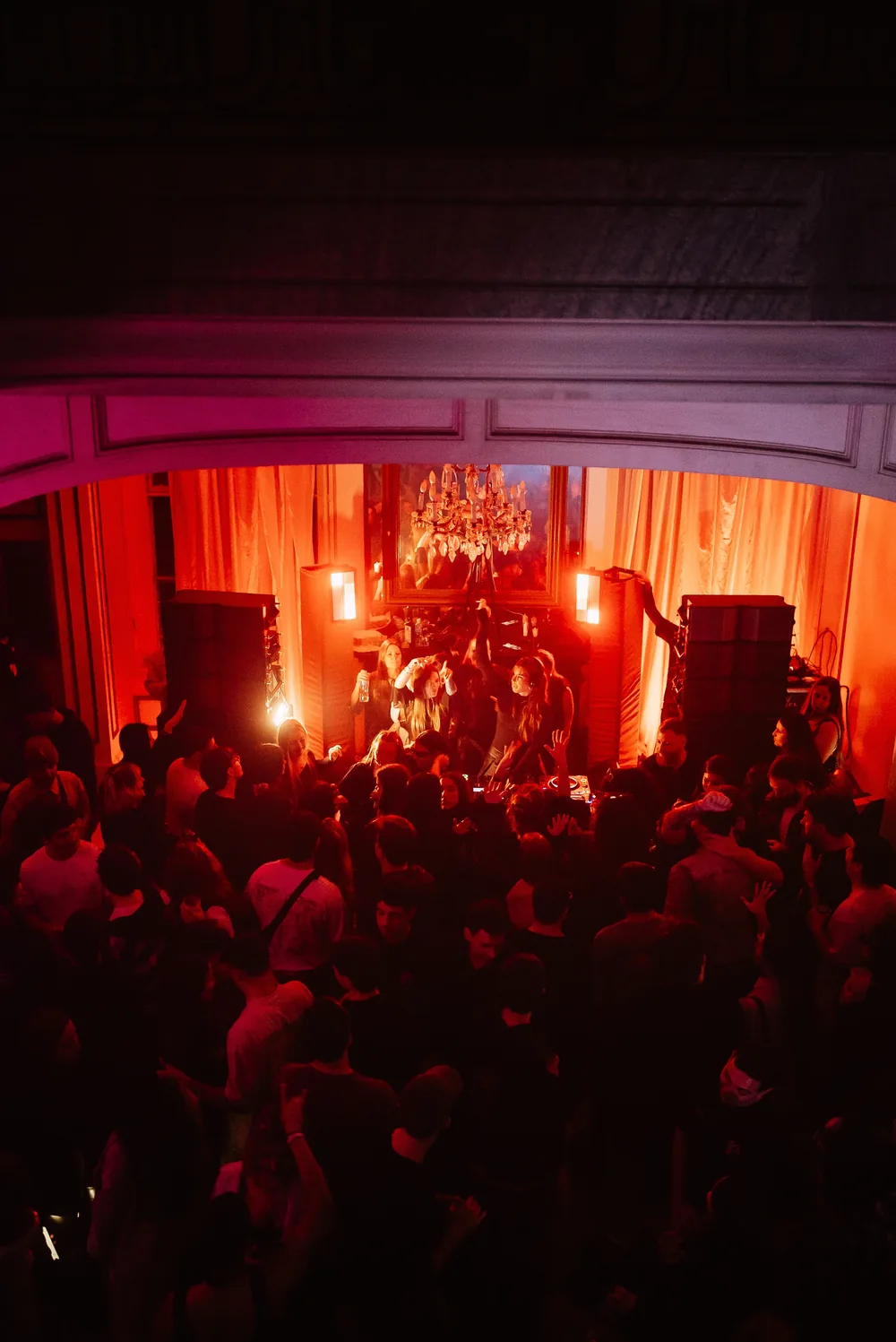 Público bailando en un evento de música electrónica con luces rojas.