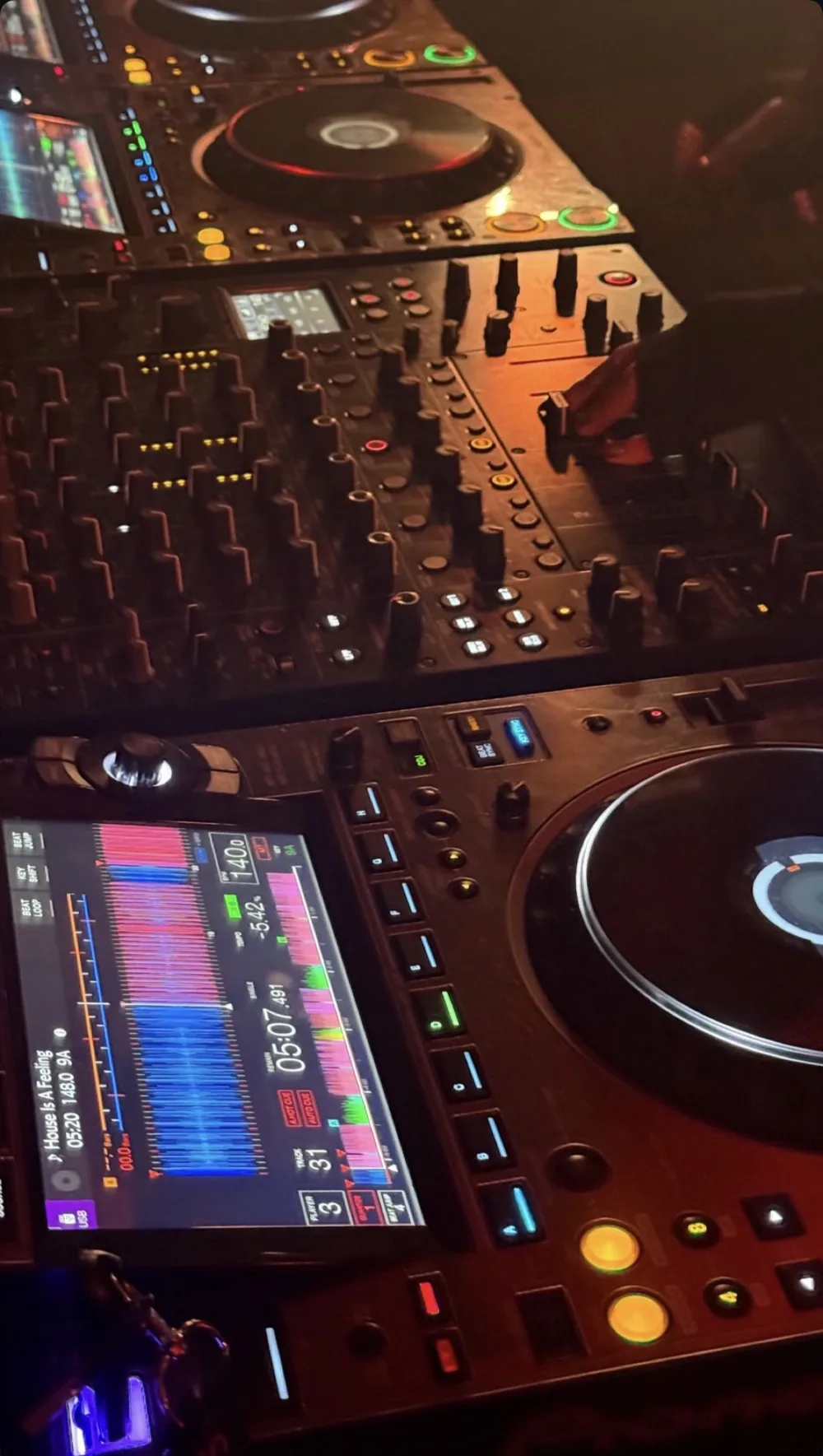 Consola Pioneer y mixer iluminados durante una sesión de práctica.